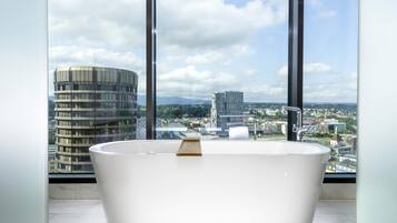 A modern bathroom with a freestanding bathtub, large windows, and a cityscape view.