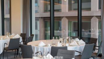 Ein Restaurant mit runden Tischen, großen Fenstern und modernem Interieur.