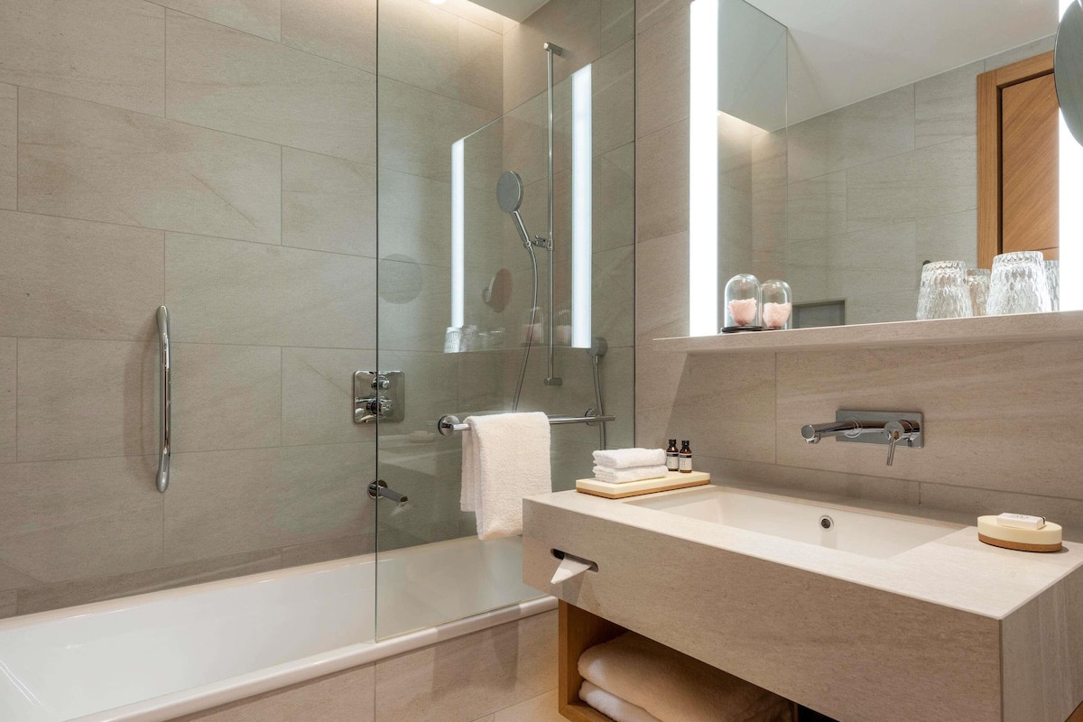 Une salle de bain moderne dotée d’une douche à parois de verre, d’une baignoire et d’un meuble-lavabo avec un miroir.