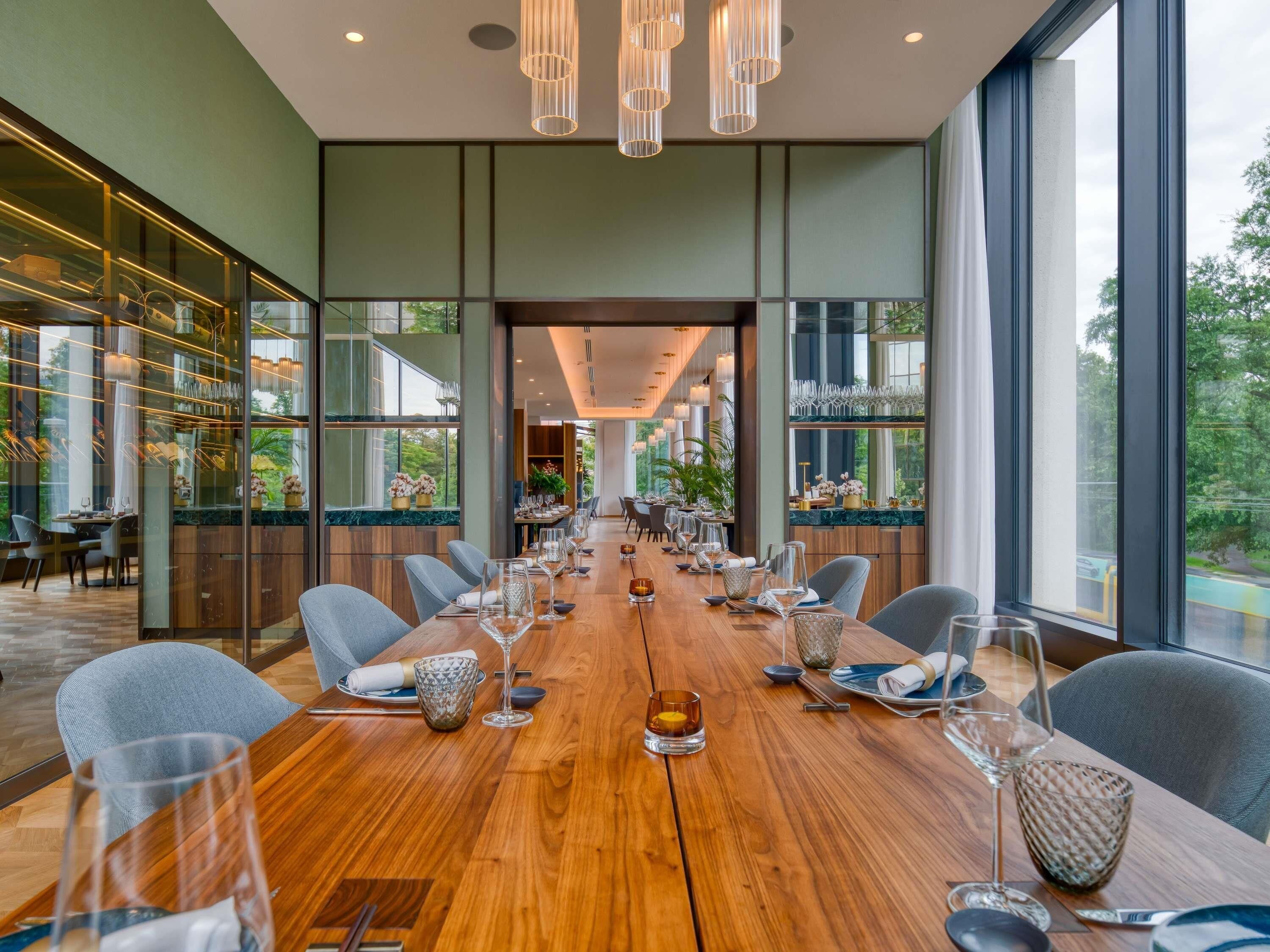 Un vaste espace dédié à la salle à manger, avec une longue table en bois dressée pour le repas, entourée de chaises modernes.