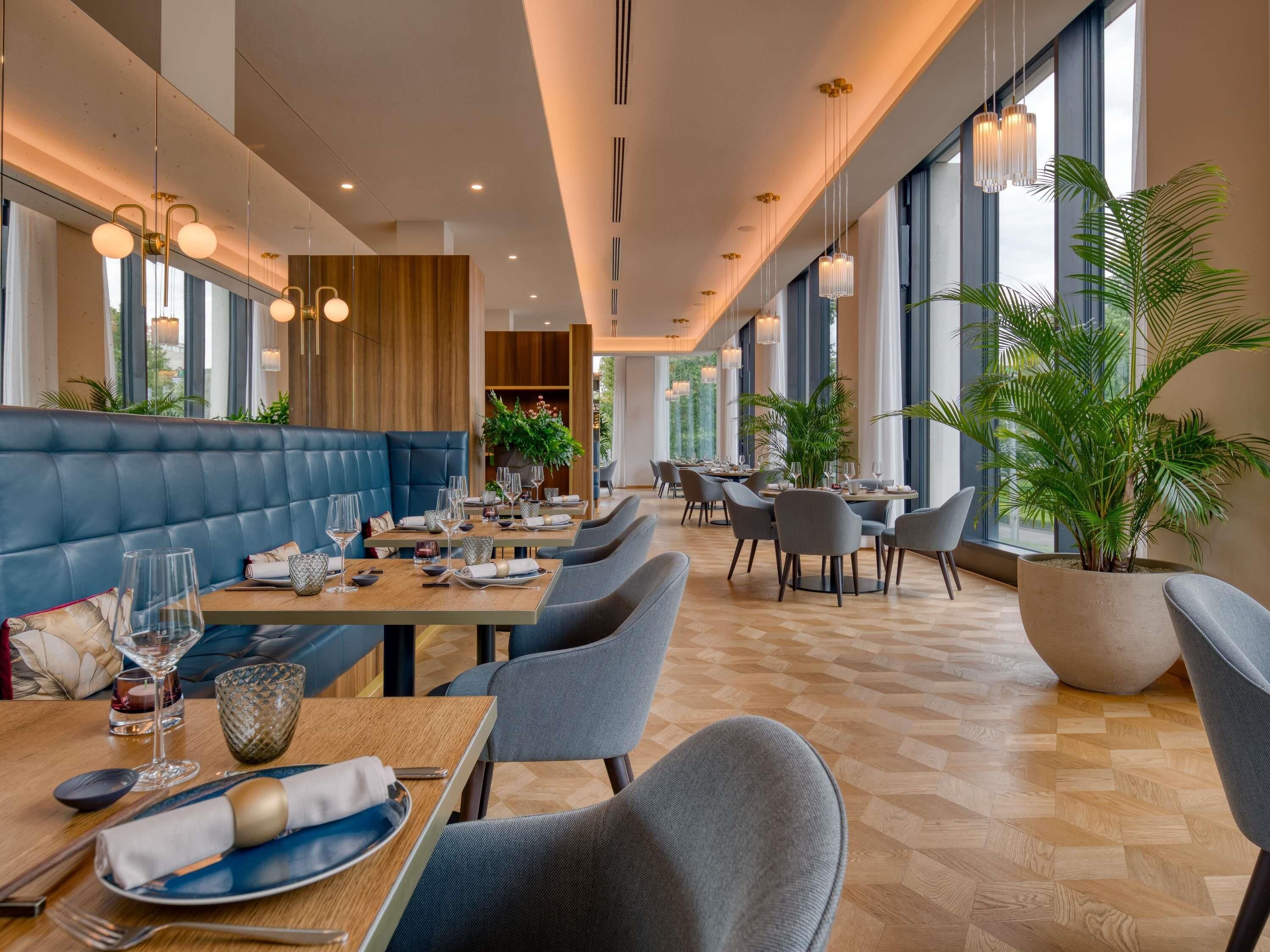 Un restaurante moderno con asientos de cuero, mesas de madera y plantas en macetas.