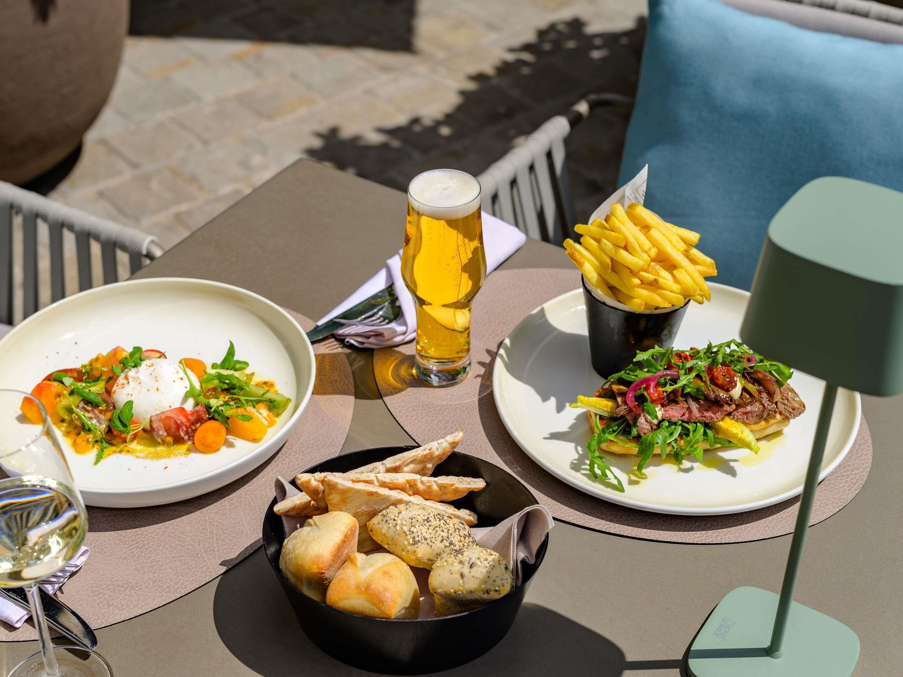 Une table dressée avec un repas composé d’un œuf poché, de légumes et d’un plat de viande, accompagné d’un verre de bière et d’une portion de frites.