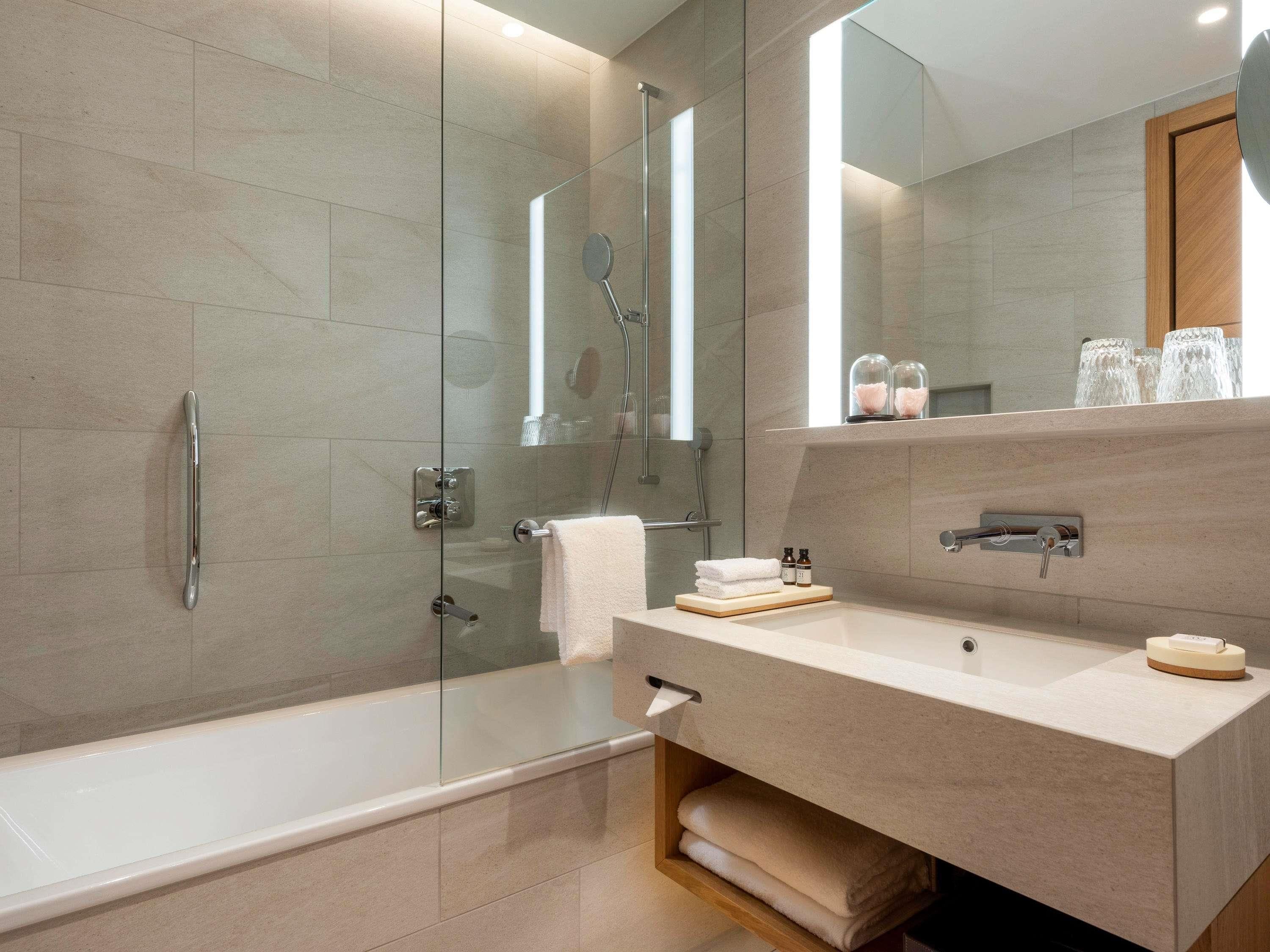 A modern bathroom with a glass-enclosed shower, a bathtub, and a vanity with a mirror.