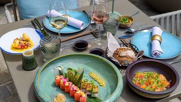 Una mesa lista para una comida, con varios platos, copas de vino y una cesta de pan.