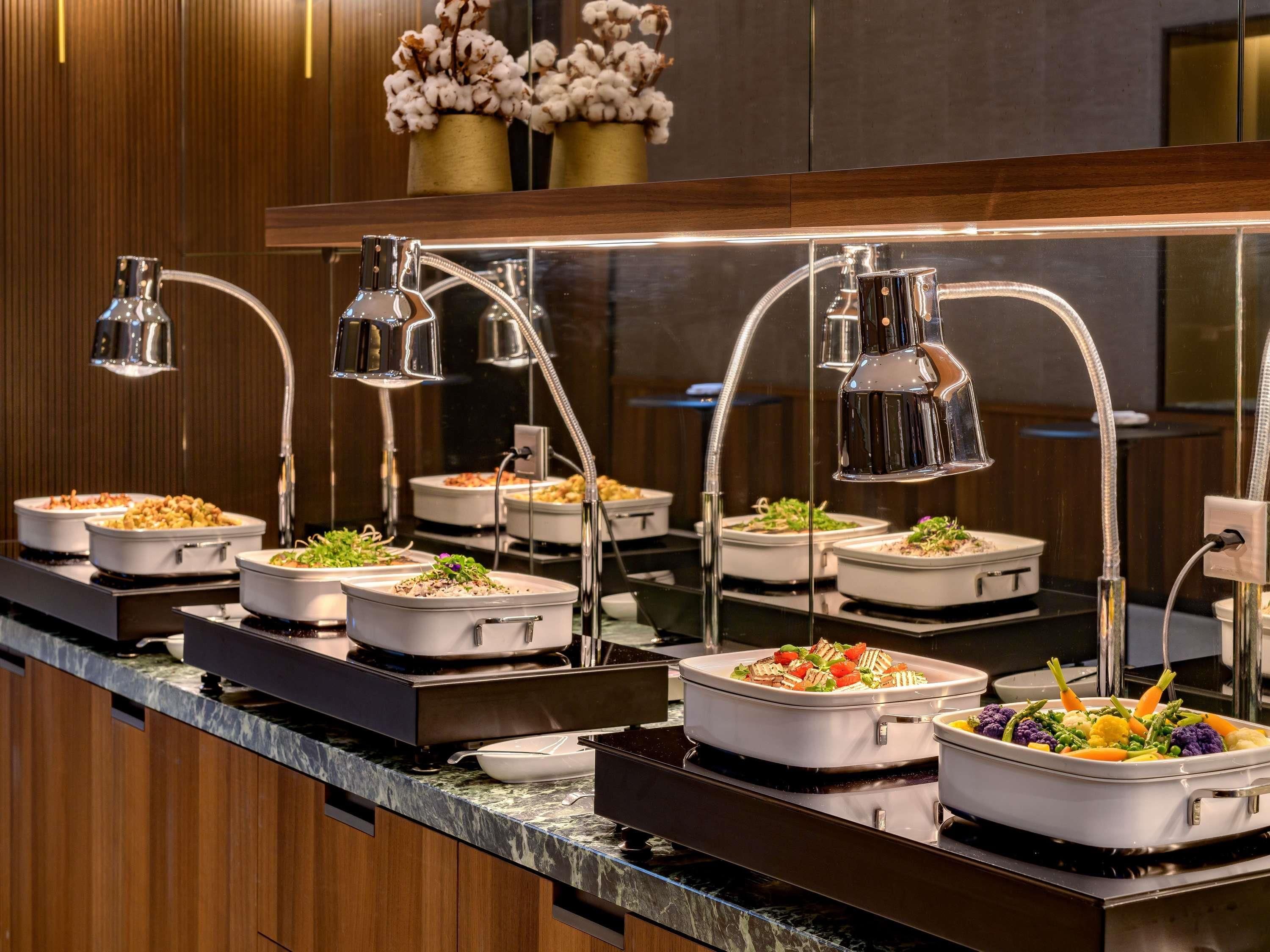 A buffet setup with multiple serving stations, each with a food container and overhead lighting.