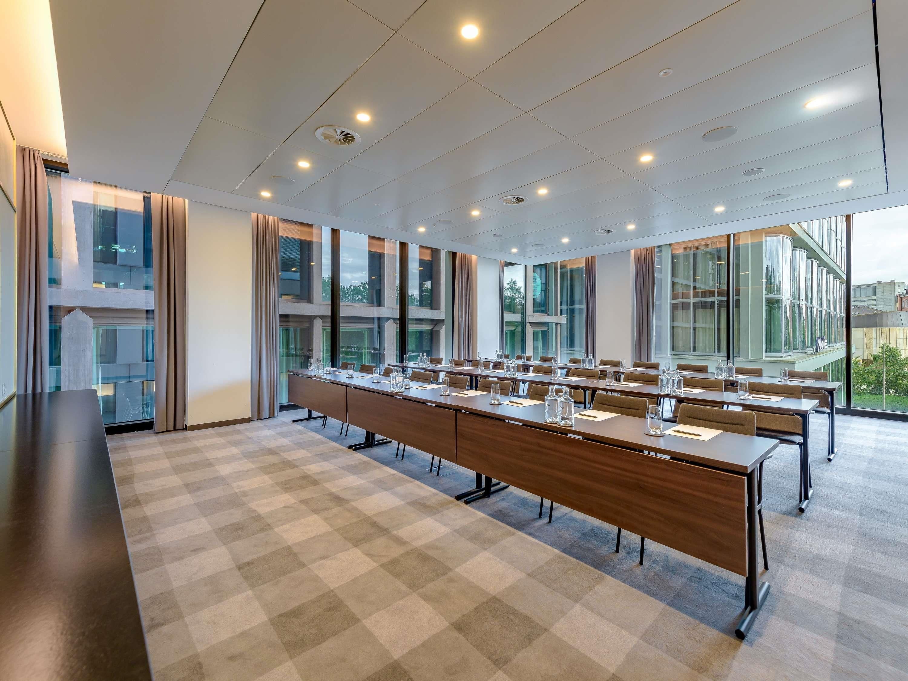 A conference room with a long table, chairs, and large windows.