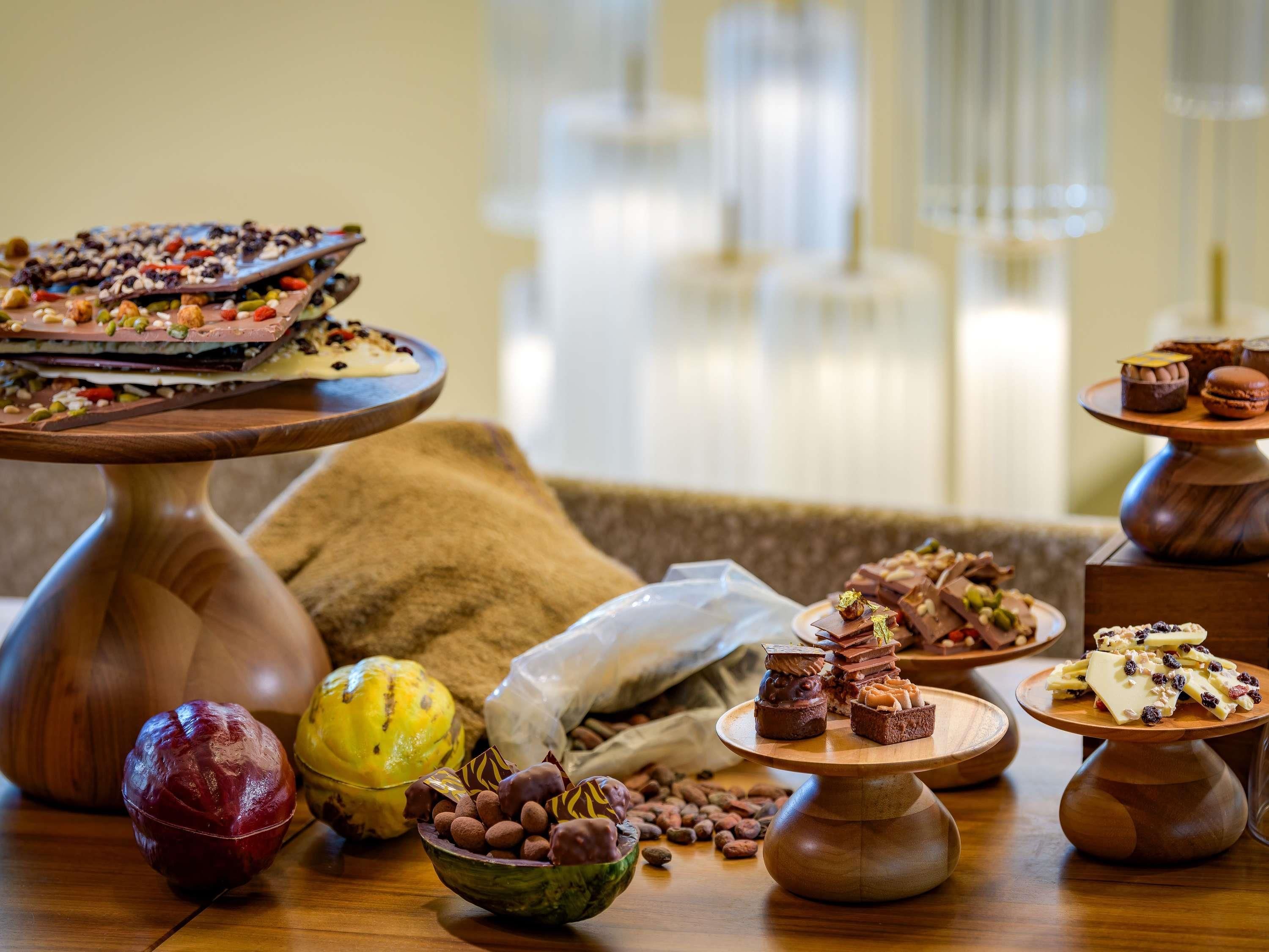 Variedad de postres sobre pedestales de madera, un cuenco de trufas de chocolate y una calabaza decorativa.