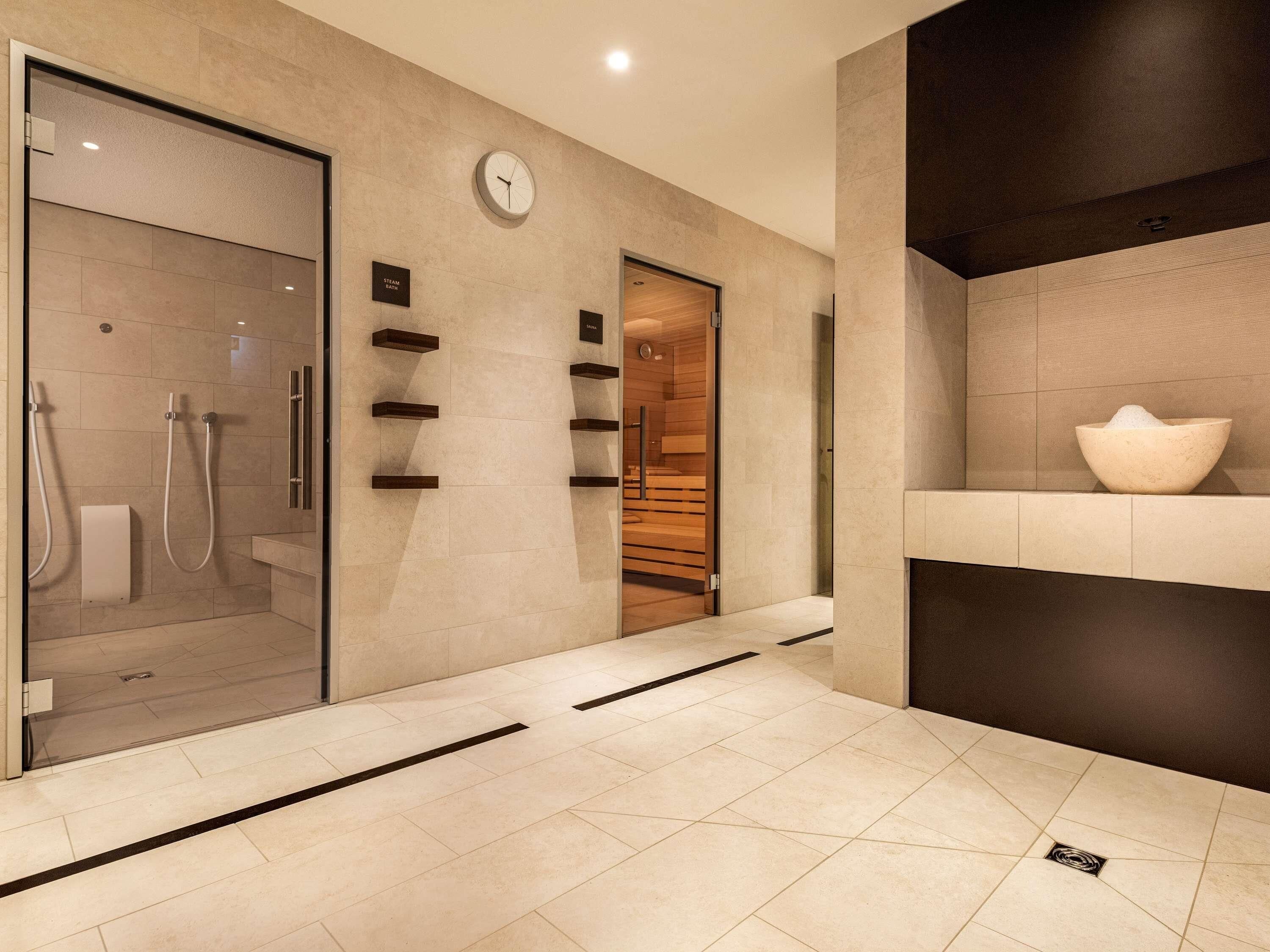 A modern bathroom with a glass shower enclosure, a wooden vanity, and a large bowl on the counter.