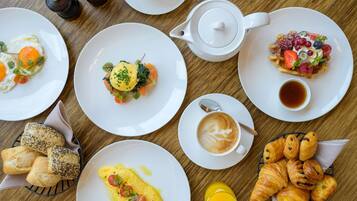 Una mesa de desayuno con diversos platos, entre ellos huevos, pasteles y una taza de té.