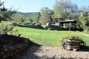 A rustic outdoor setting with a stone wall, a wooden barrel, and a thatched-roof structure.