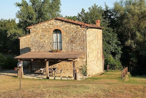 A stone building with a tiled roof, a small porch, and a window.