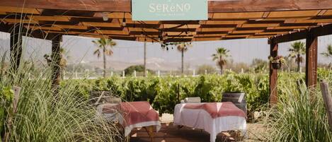 Una pérgola de madera con un letrero que dice "Sereno Valley Massage" y dos camillas de masaje debajo.