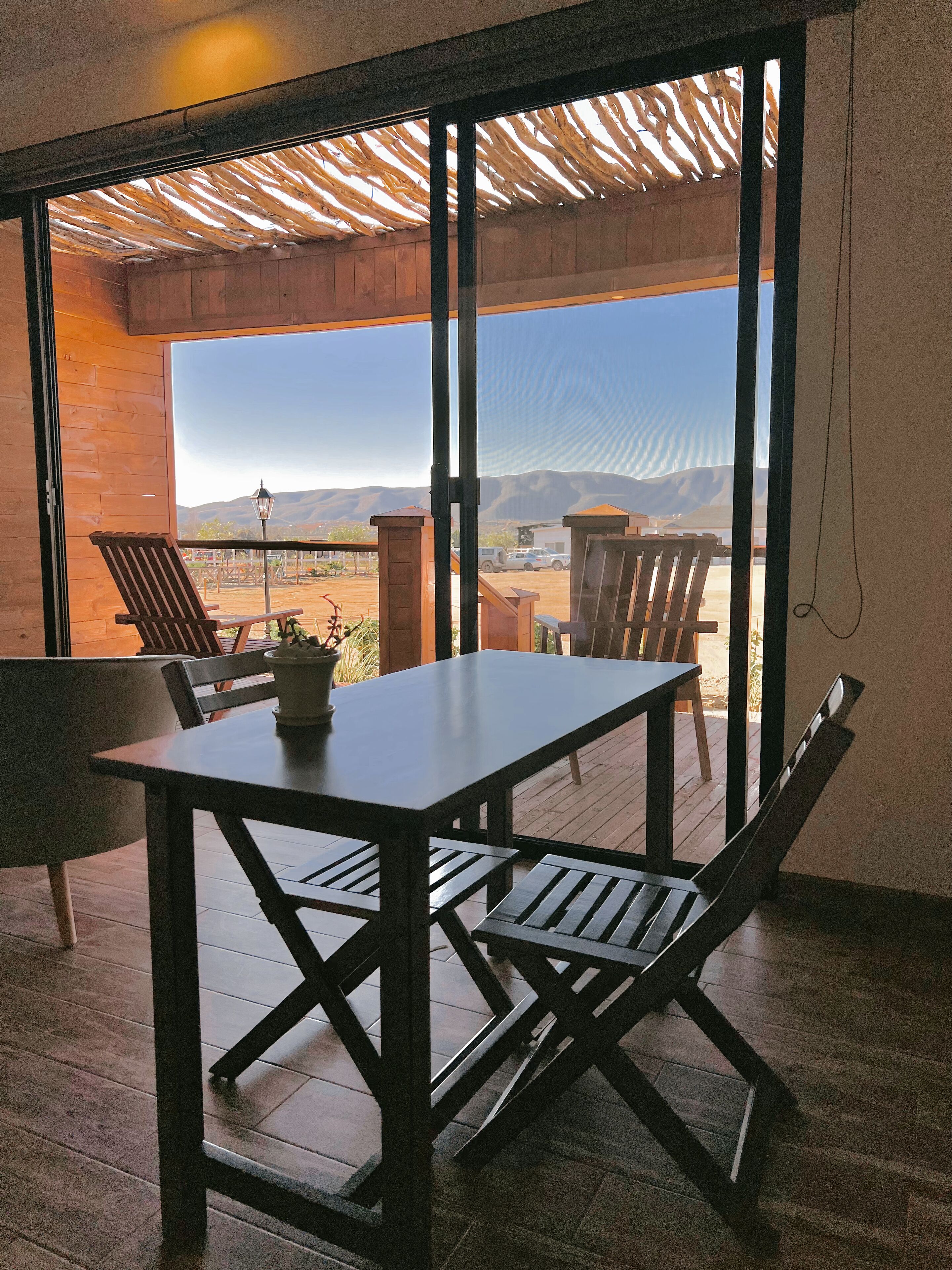 A wooden table and chairs in a room with large windows overlooking a desert landscape.