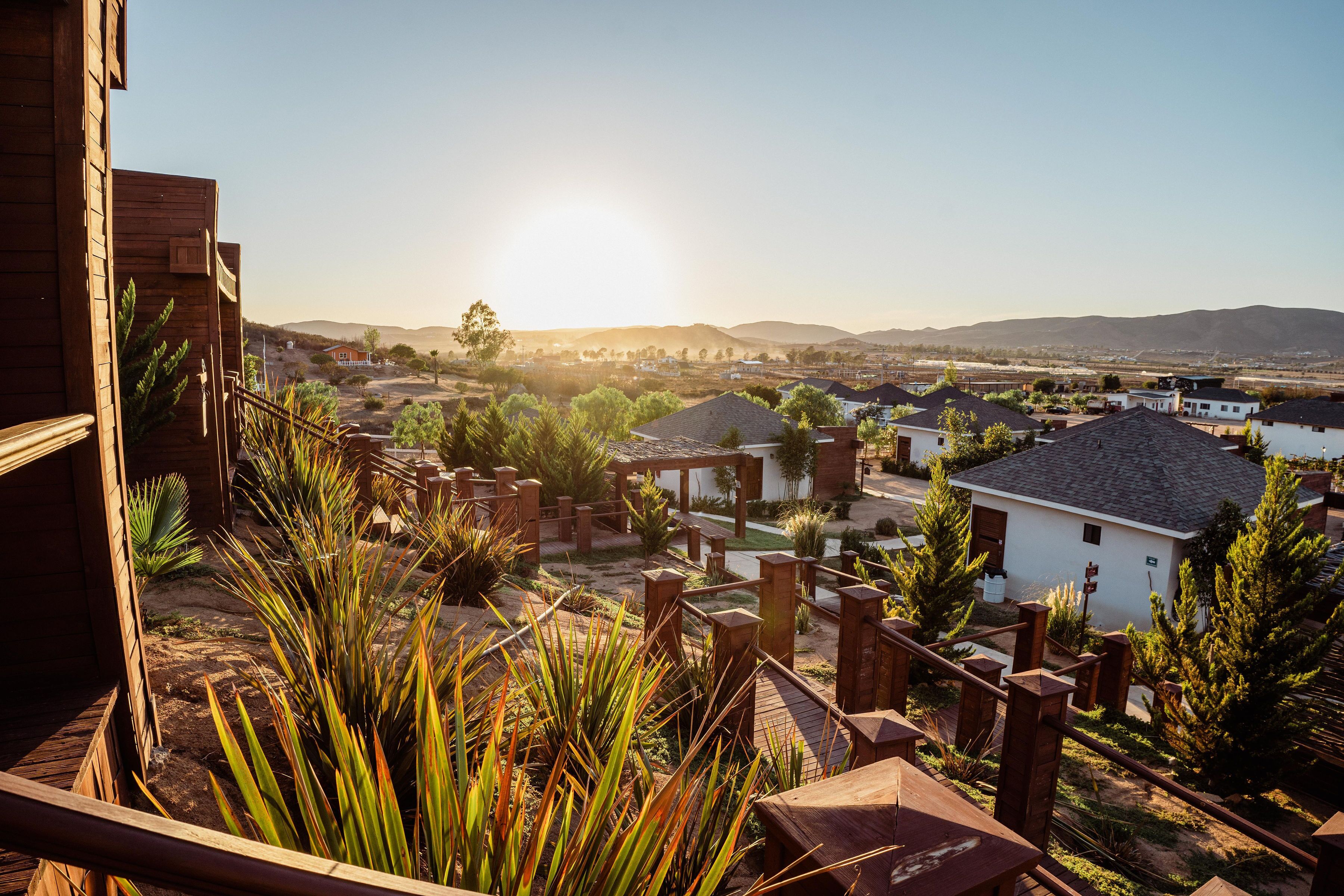 A residential area with a wooden deck, a white building, and a view of distant hills.