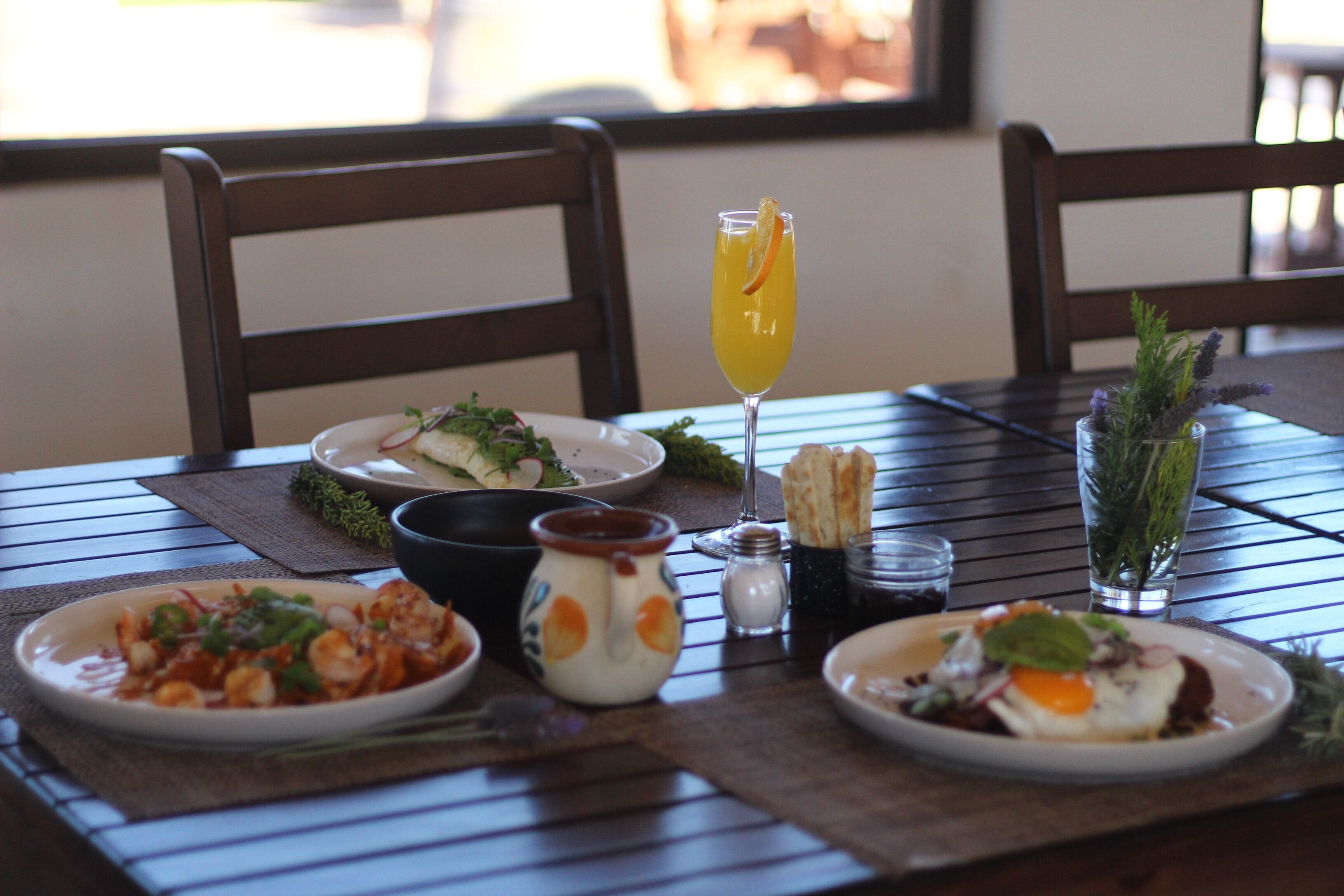 A dining table with various dishes, a glass of orange juice, and condiments.
