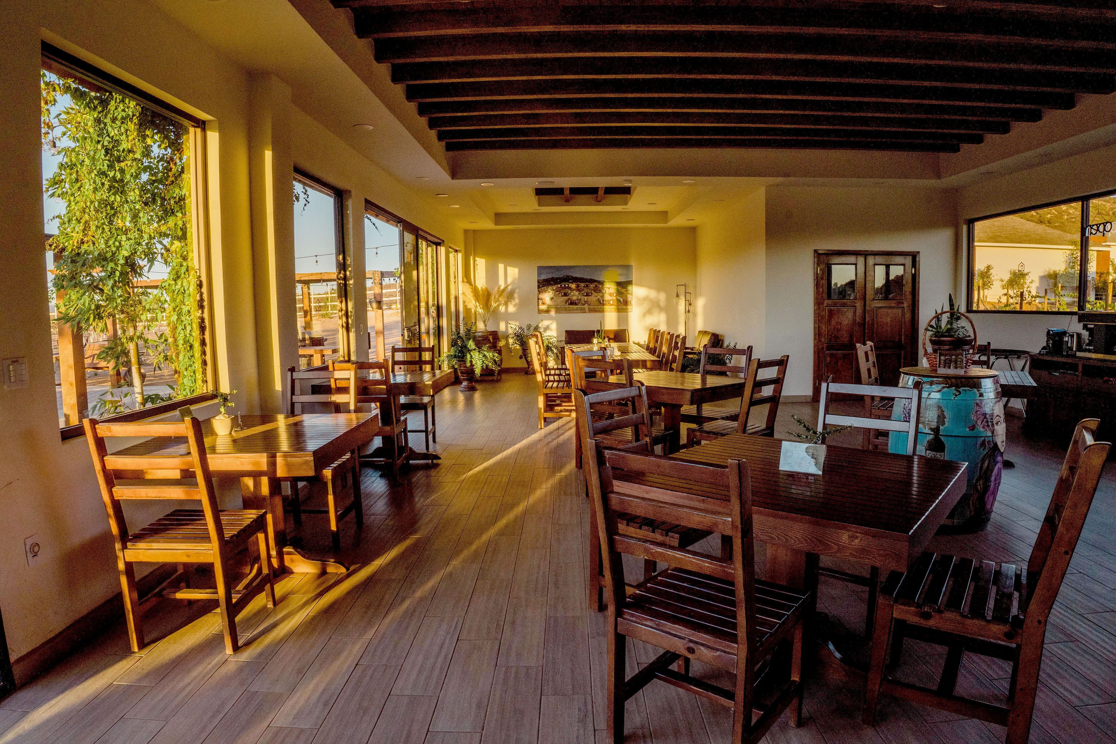 Un vaste espace dédié à la salle à manger, avec des tables et des chaises en bois, de grandes fenêtres et une vue sur l’extérieur.
