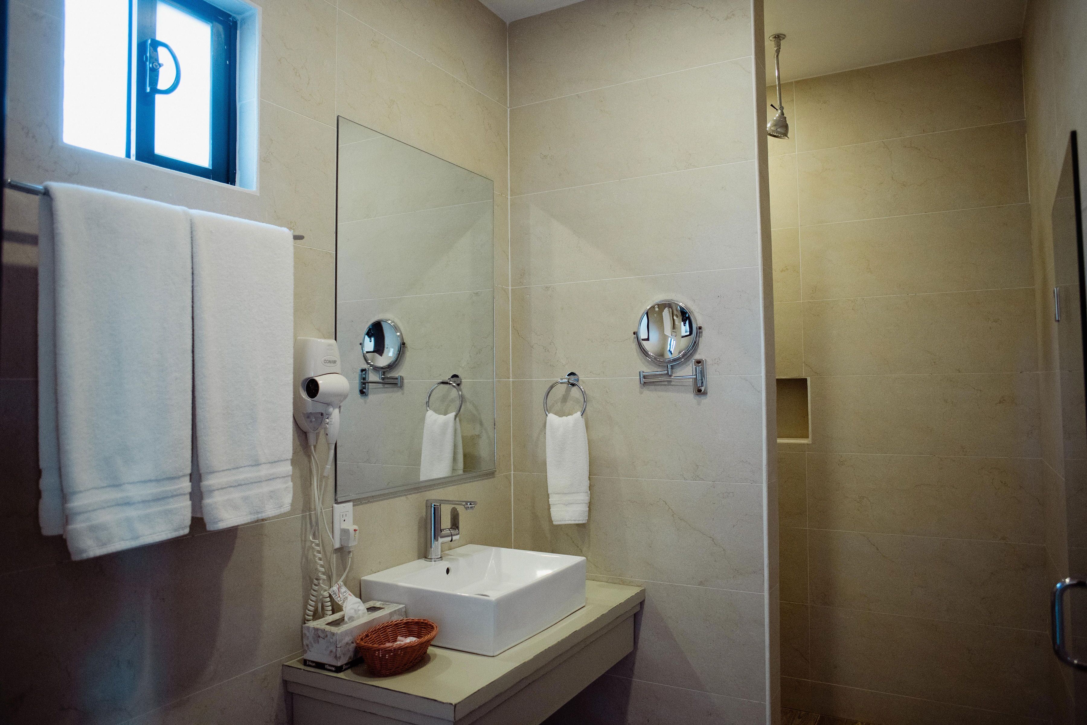 A modern bathroom with a large mirror, a sink, and a shower.