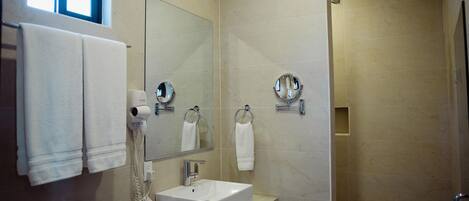 A modern bathroom with a large mirror, a sink, and a shower.