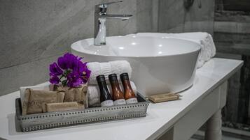 Een badkamer met een grote witte wasbak, een spiegel en een schaal met toiletartikelen.