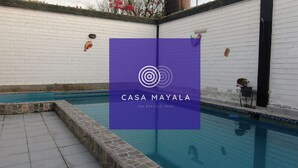 Ein Swimmingpool mit einer weißen Backsteinmauer und einem violetten Banner mit dem Text "CASA MAYALA SAN BARTOLO, PERU".