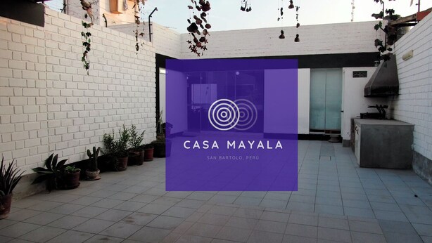 Ein Innenhof mit weißen Backsteinmauern, Blumentöpfen und einem violetten Schild für CASA MAYALA in San Bartolomé, Peru.