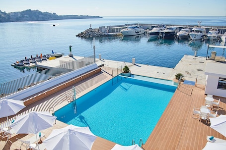 Una piscina al aire libre de temporada, sombrillas