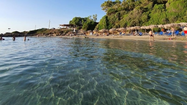 A beach with clear water, umbrellas, and people. - Villa Olympia Skafidia beach (Skafidia Pirgos ilias)