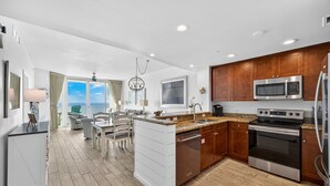 A modern kitchen with wooden cabinets, stainless steel appliances, and a view to the outside.
