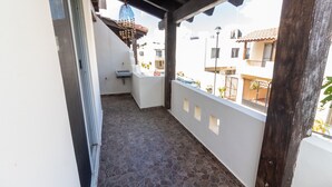 Ein Balkon mit Steinboden, weißen Wänden und einer Holzträgerkonstruktion.