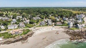 Vista aérea de una zona residencial costera con casas, una playa y un litoral rocoso.
