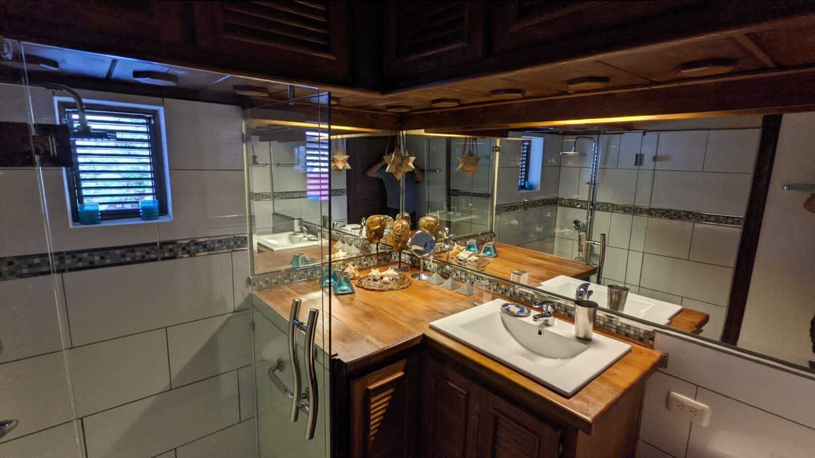 A modern bathroom with a glass shower enclosure, a wooden vanity, and a large mirror reflecting the room.