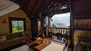A cozy living room with a sofa, coffee table, and a view of the ocean through a balcony. - Ecolodge Vistamar (Enriquillo)