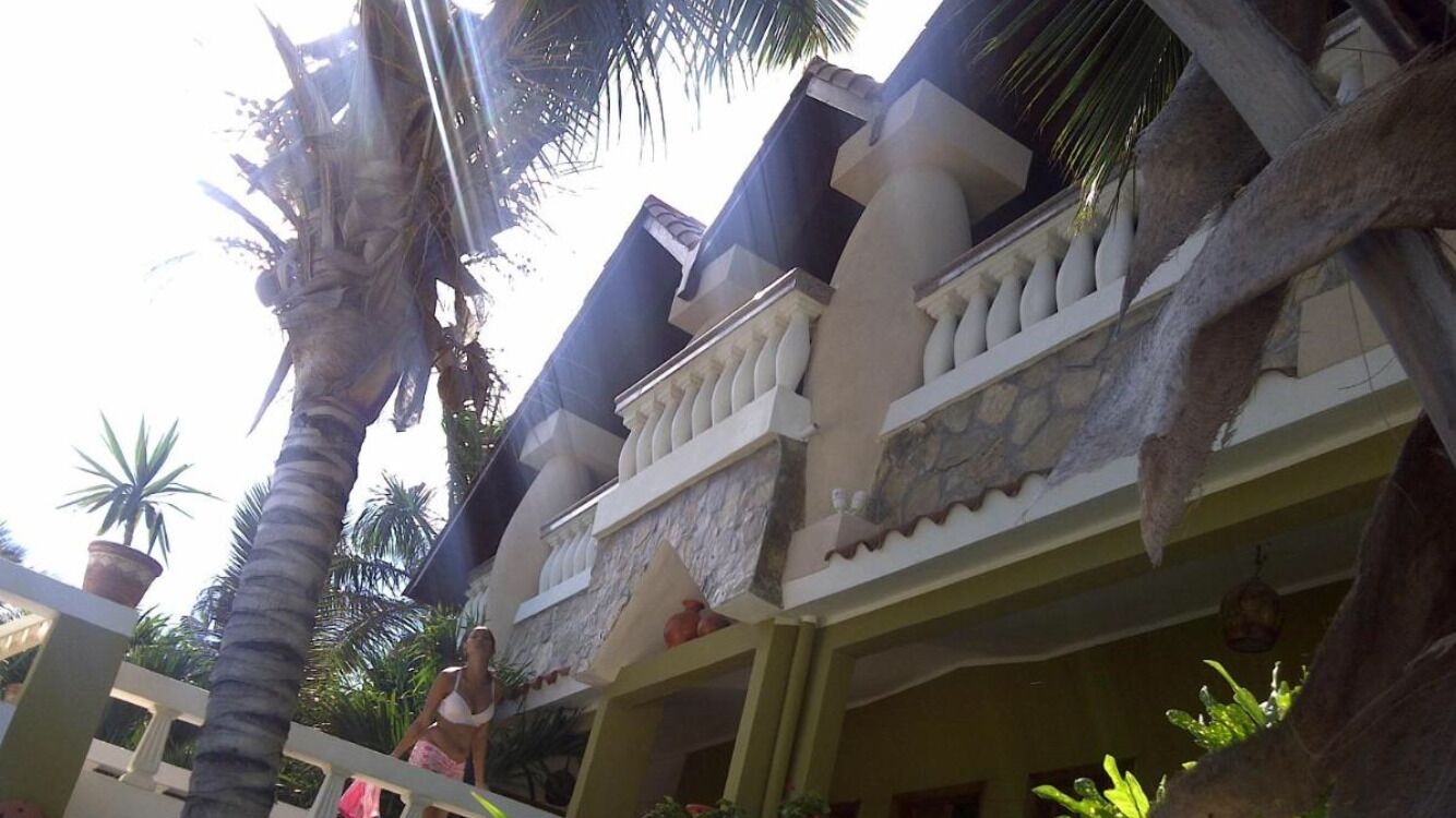 Ein Gebäude mit Balkon, Palmen und einer Topfpflanze.