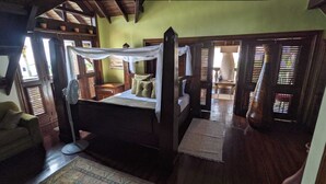 A bedroom with a four-poster bed, wooden flooring, and a view of the adjacent room through a doorway. - Ecolodge Vistamar (Enriquillo)