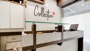 A modern reception desk with a glass top, a laptop, and a sign that reads "Collection". - Shri Sai Residency (Jaipur)