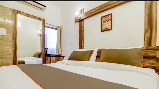 A hotel room with a large bed, a desk, and a mirror. - Shri Sai Residency (Jaipur)