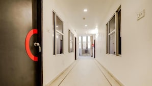 A long, narrow hallway with white walls and doors on both sides, leading to a bright room at the end. - Shri Sai Residency (Jaipur)