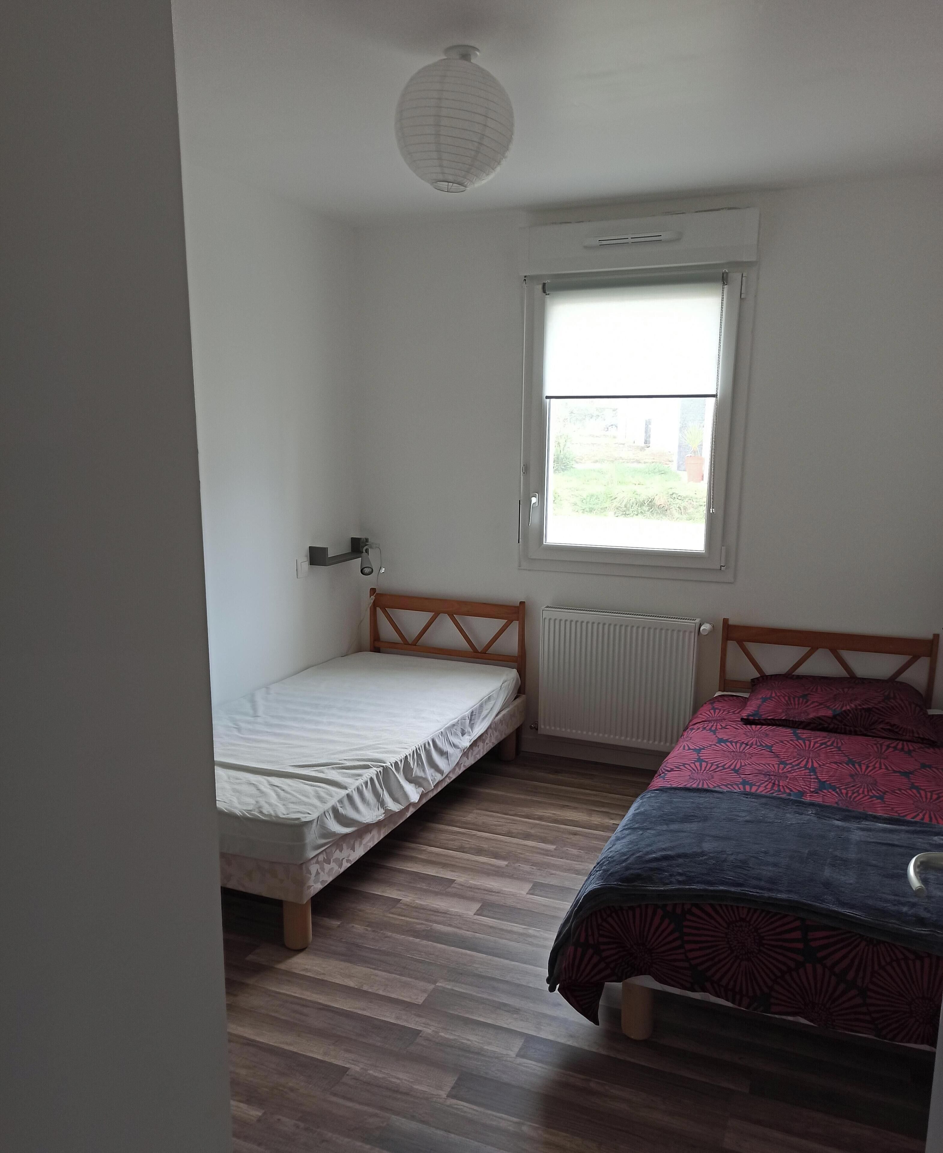 Een slaapkamer met een bed, een raam en een radiator.