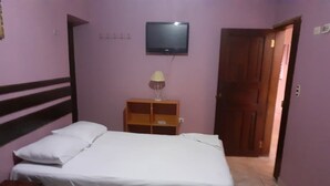 Una habitación con dos camas, un televisor montado en la pared y una puerta de madera.