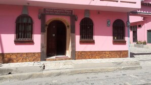 Un edificio rosa con un letrero que dice 'Hotel Imporio Maya'.