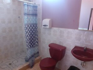 Un baño con cortina de ducha estampada, un inodoro rojo y un lavabo rojo.