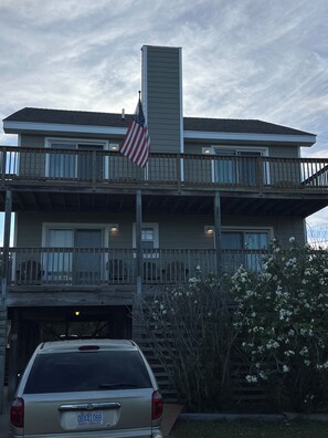 Een twee verdiepingen tellend huis met een garage, een Amerikaanse vlag en een auto ervoor.
