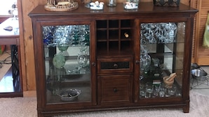 Een houten kast met glazen deuren, gevuld met kristal en decoratieve objecten.