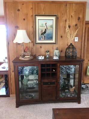 A wooden cabinet with glass doors displaying glassware and decorative items.