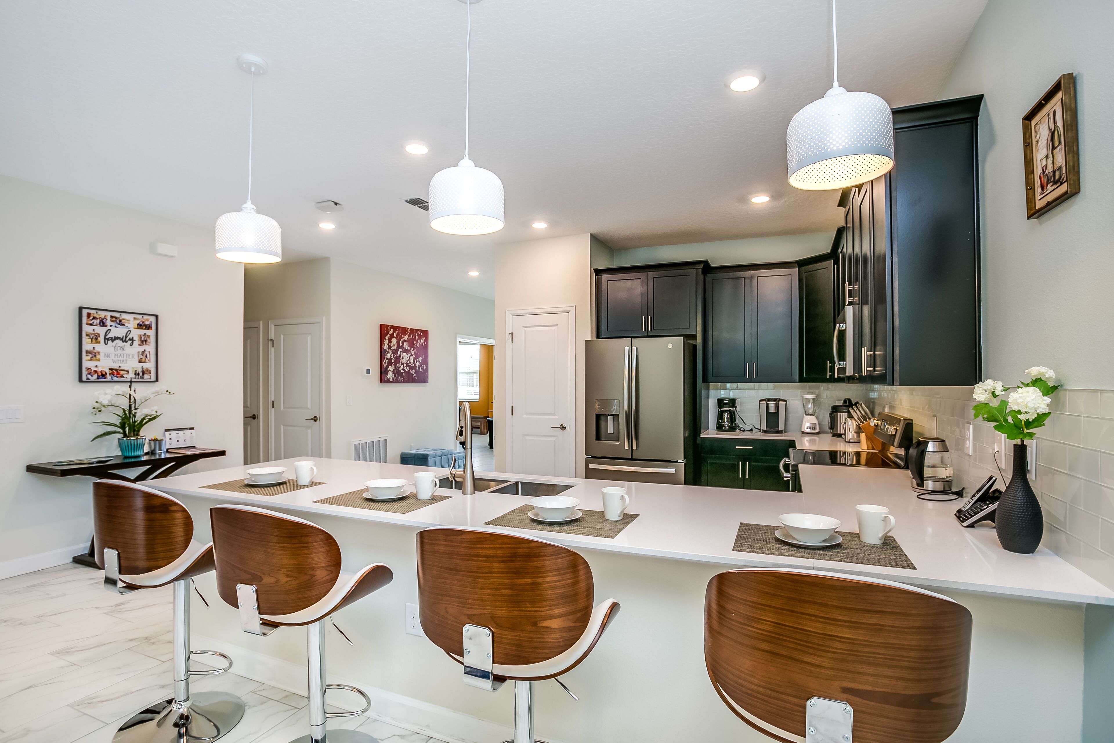 A modern kitchen with a central island, bar stools, and pendant lighting.