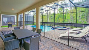 An outdoor patio with a pool, lounge chairs, and a dining area with wicker furniture. - Serenity by Your Private Pool! No Rear Neighbors! Resort Near DISNEY! (Kissimmee)