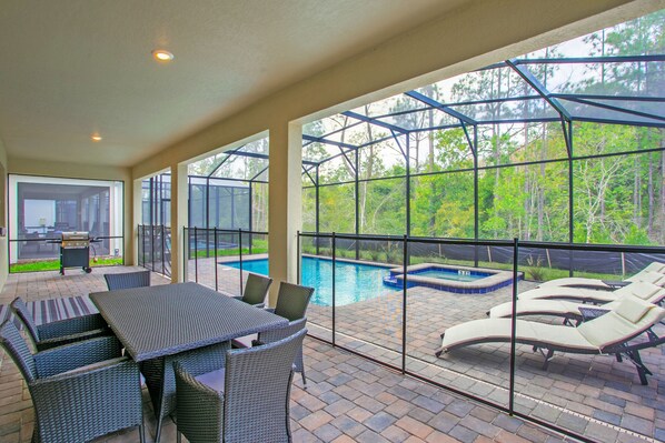 Une terrasse extérieure avec une piscine, des chaises longues et un coin repas aménagé avec des meubles en osier.