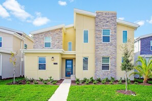 A modern two-story house with a stone facade, a front entrance, and a well-maintained lawn.