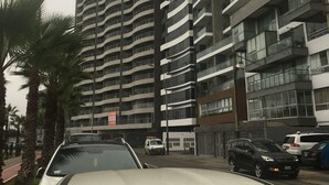 A multi-story residential building with balconies, a parking area, and palm trees. - MASSIVE 7 BEDROOM MALECON DUPLEX PENTHOUSE (Urb Santa Cruz)