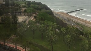 A coastal view with a road leading to the beach, palm trees, and a distant mountain. - MASSIVE 7 BEDROOM MALECON DUPLEX PENTHOUSE (Urb Santa Cruz)